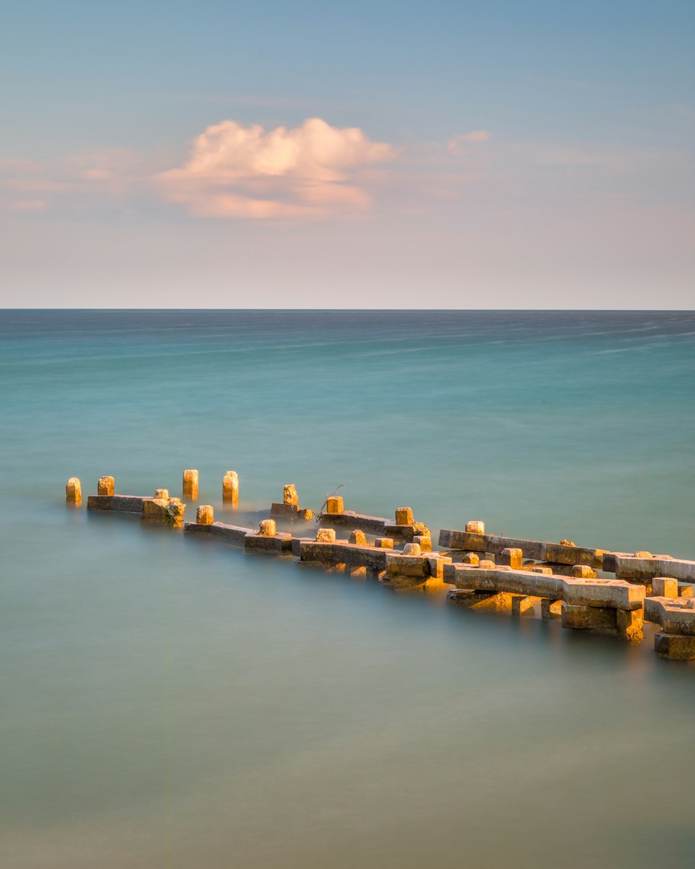 brown wooden dock on sea under blue sky during daytime