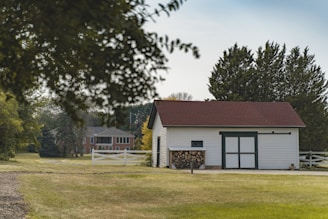 white and brown house near green tree under white clouds during daytime