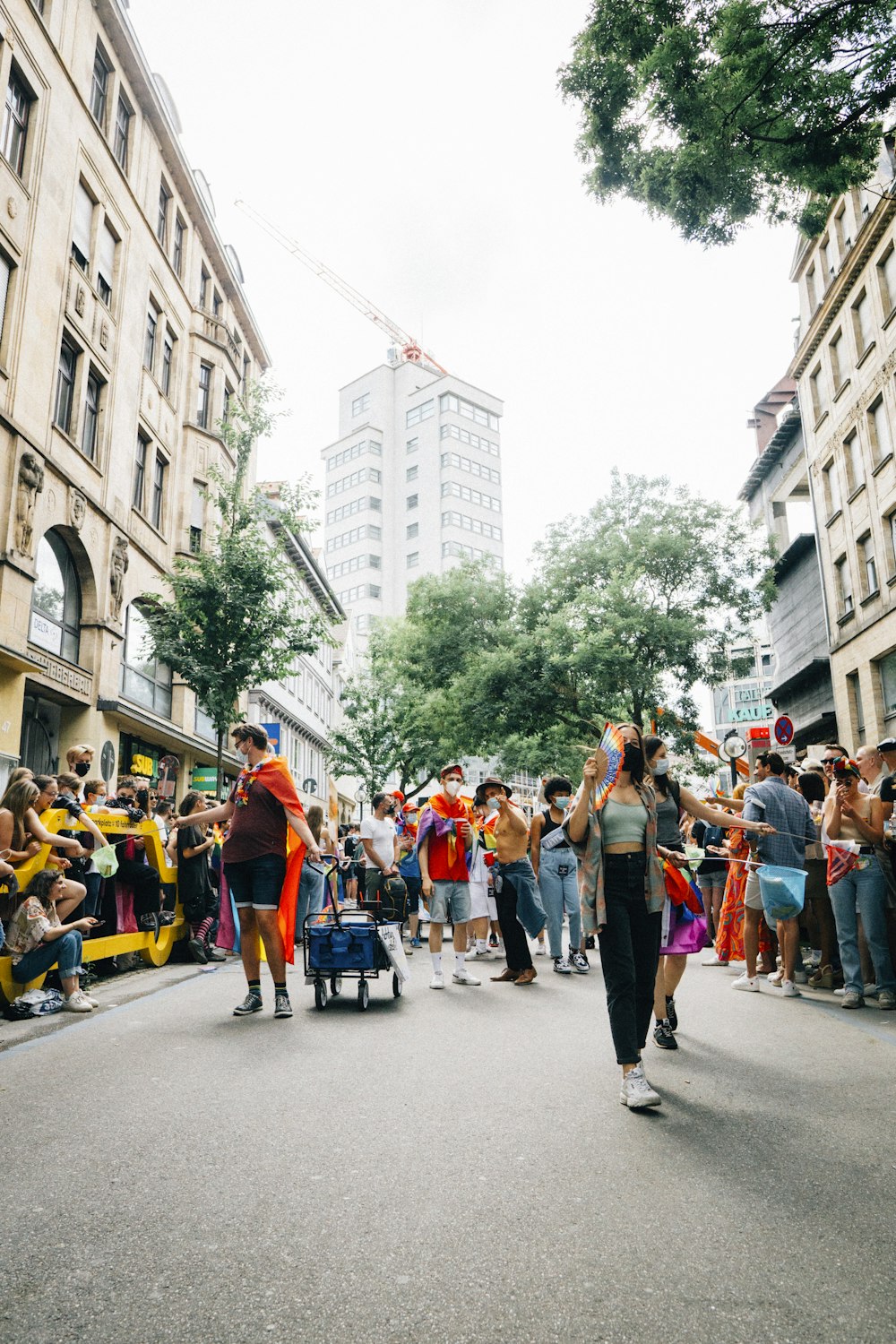 a crowd of people walking down a street next to tall buildings