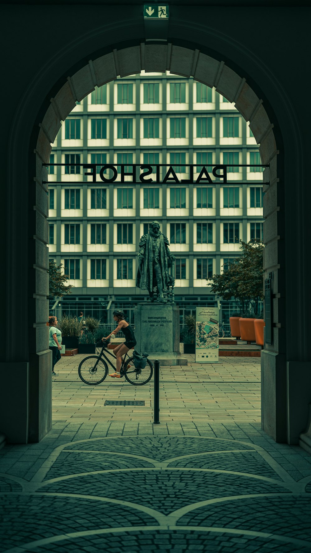 Mann in schwarzer Jacke fährt tagsüber Fahrrad in der Nähe des Gebäudes