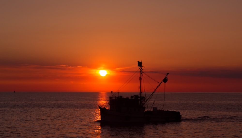 silhouette of ship on sea during sunset