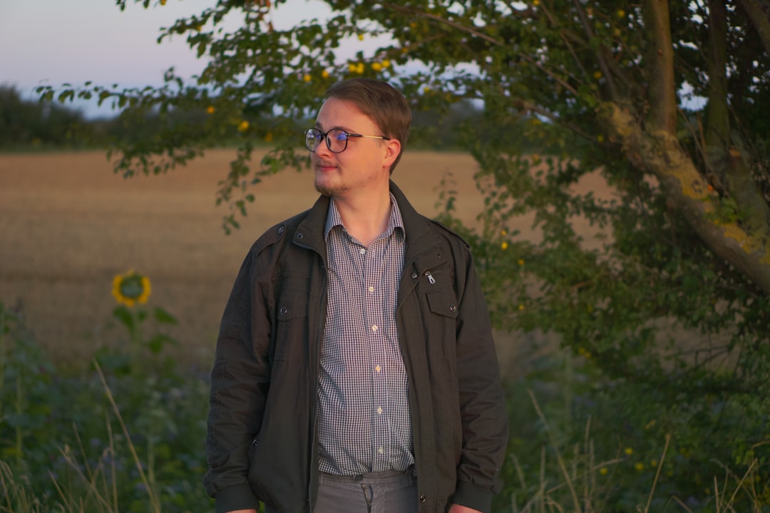 man in black jacket standing on green grass field during daytime