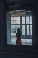 woman in red dress standing in front of window