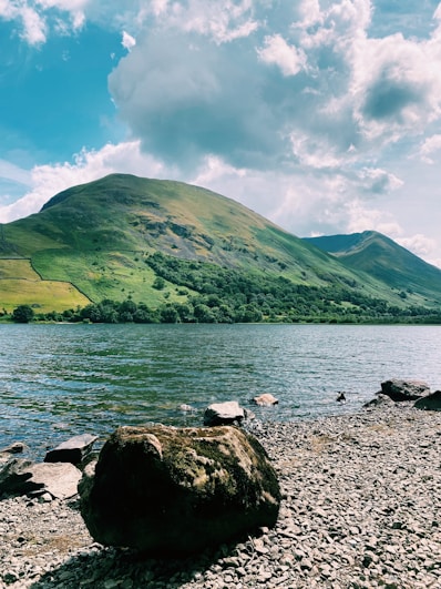 green mountain beside body of water during daytime