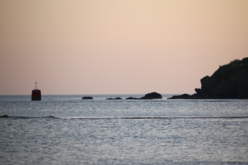 silhouette of rock formation on sea during sunset