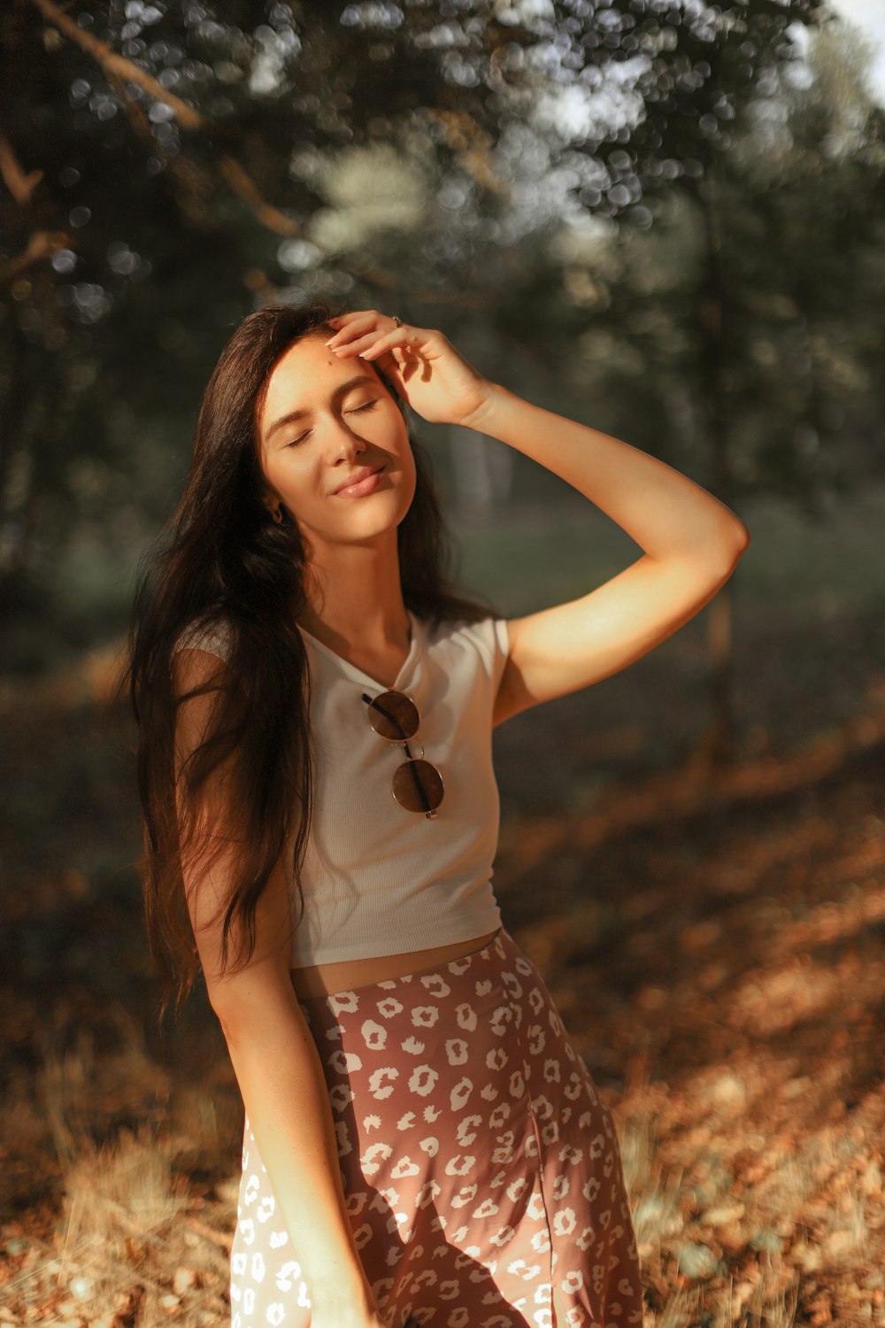 Mujer en camiseta blanca sin mangas y falda de lunares en blanco y negro de pie en el bosque