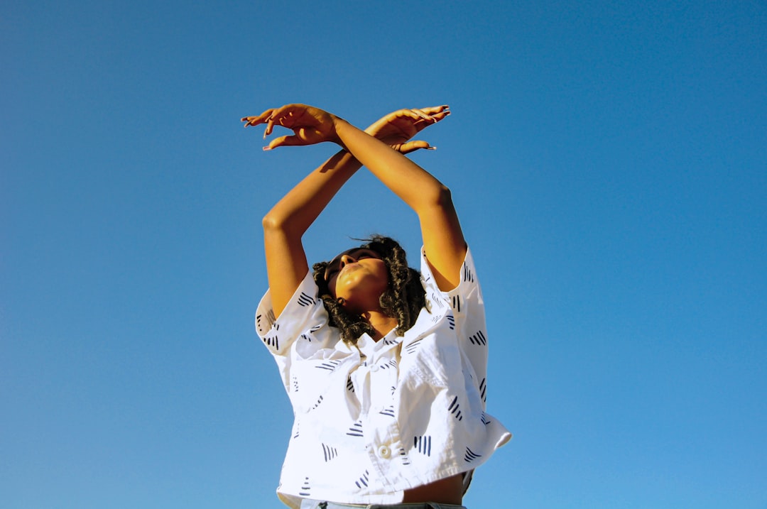 woman in white button up shirt raising her hands