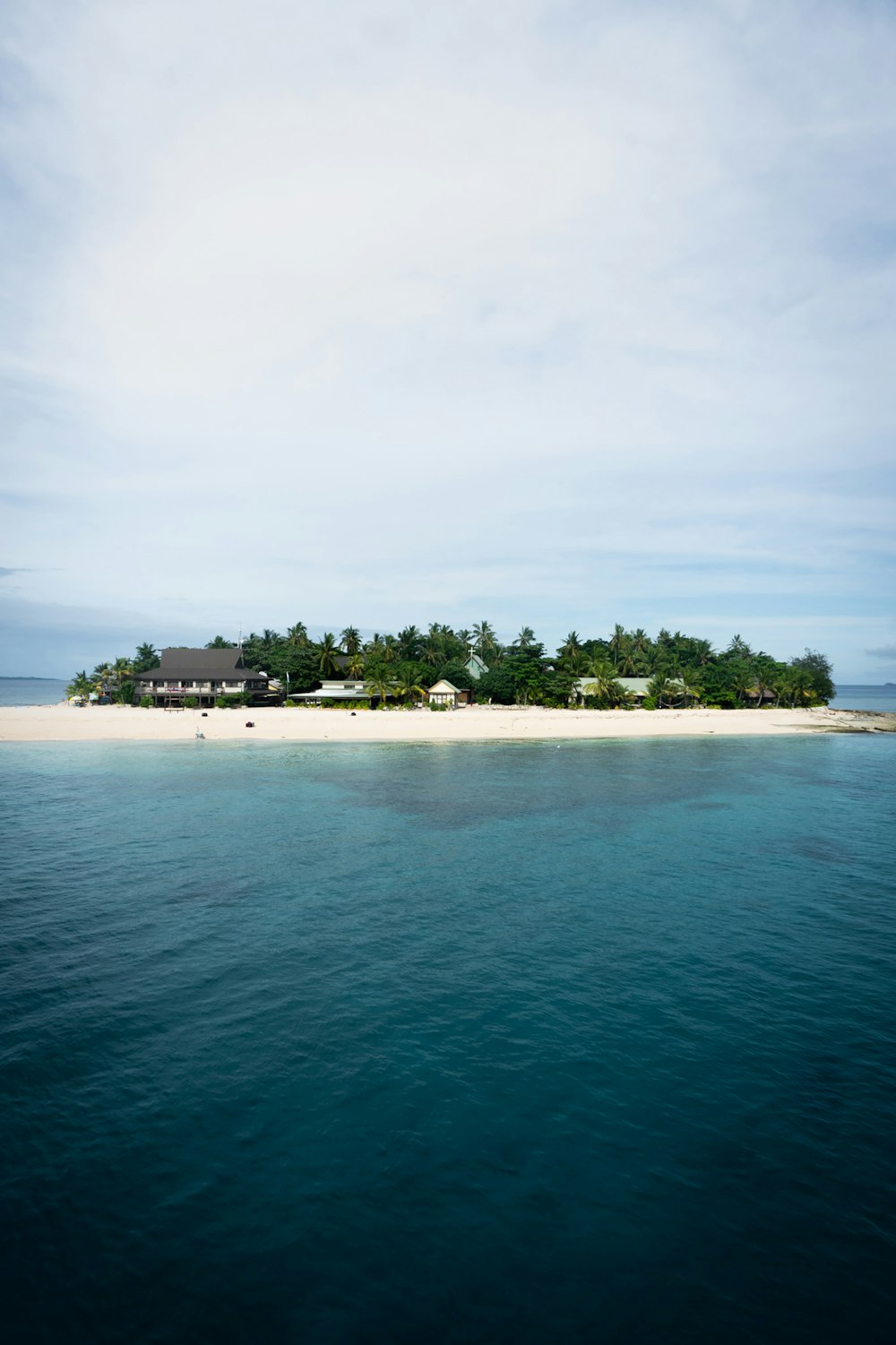 green trees on island surrounded by water under white clouds during daytime