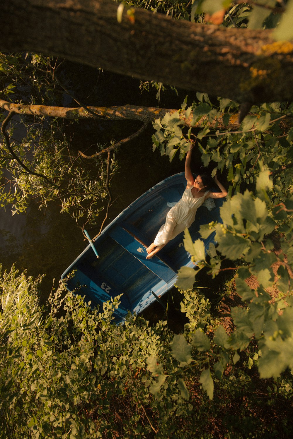 woman in white long sleeve shirt and blue denim jeans sitting on blue boat during daytime