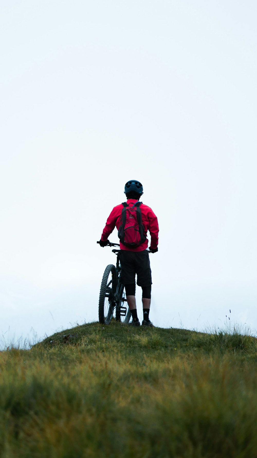 homme en veste rouge faisant du vélo sur un champ d’herbe verte pendant la journée