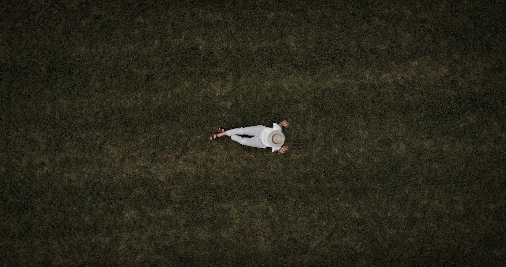 woman in white long sleeve shirt lying on green grass field during daytime