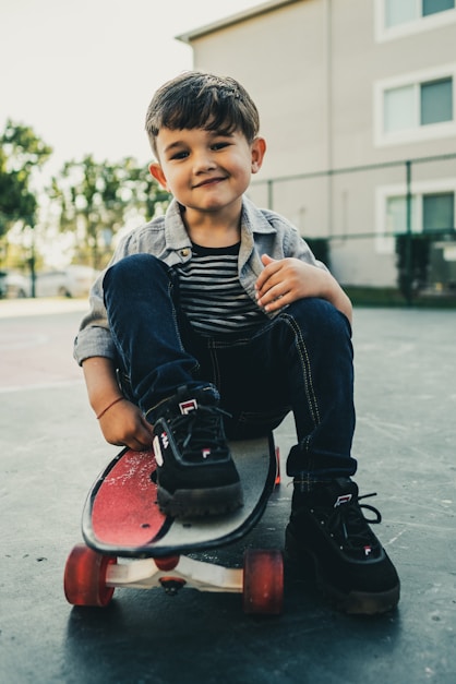 boy in blue denim jacket and blue denim jeans sitting on red round chair