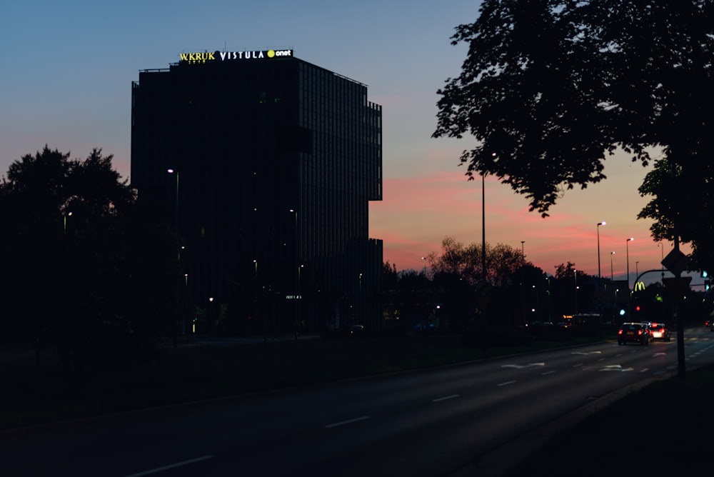 a city street at dusk with a building in the background