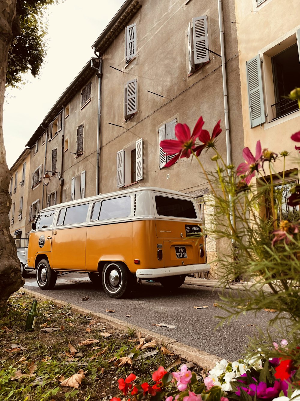 orange and white van parked beside brown concrete building during daytime