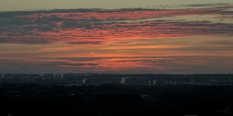A dramatic photo of a mushroom cloud rising over a distant horizon at sunset.