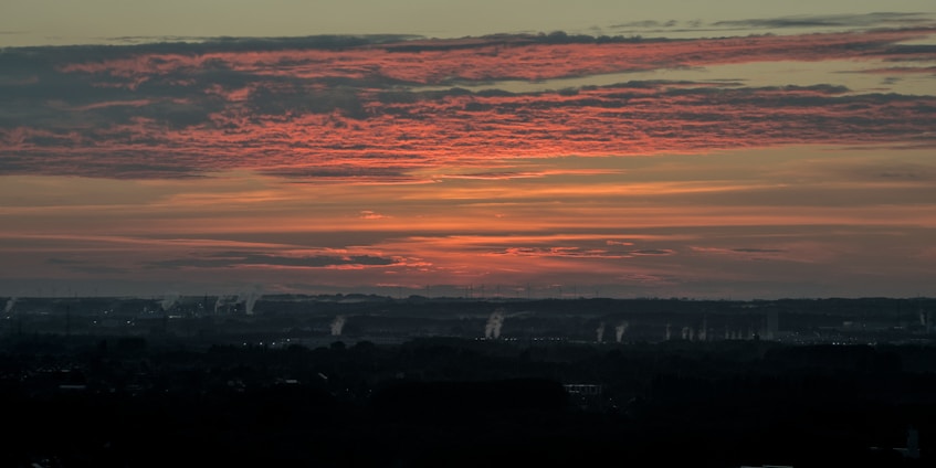 A dramatic photo of a mushroom cloud rising over a distant horizon at sunset.