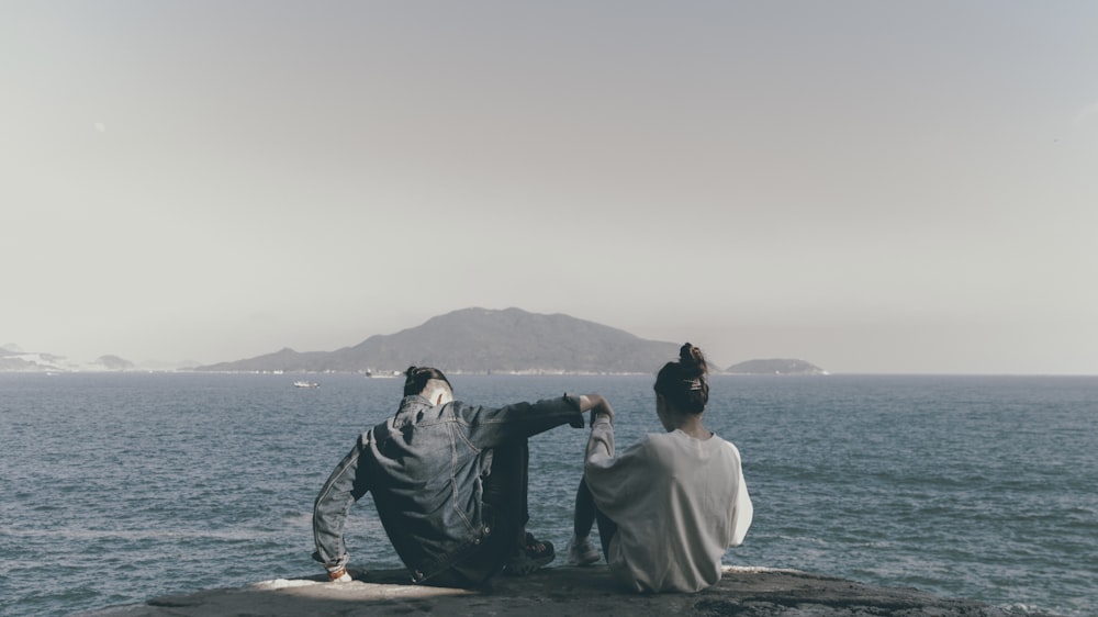 man and woman sitting on brown wooden dock during daytime