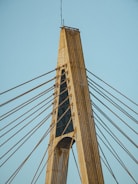 A modern cable-stayed bridge tower with numerous cables extending outward. The structure is made of concrete and steel, showcasing an architectural design with vertical and diagonal elements.