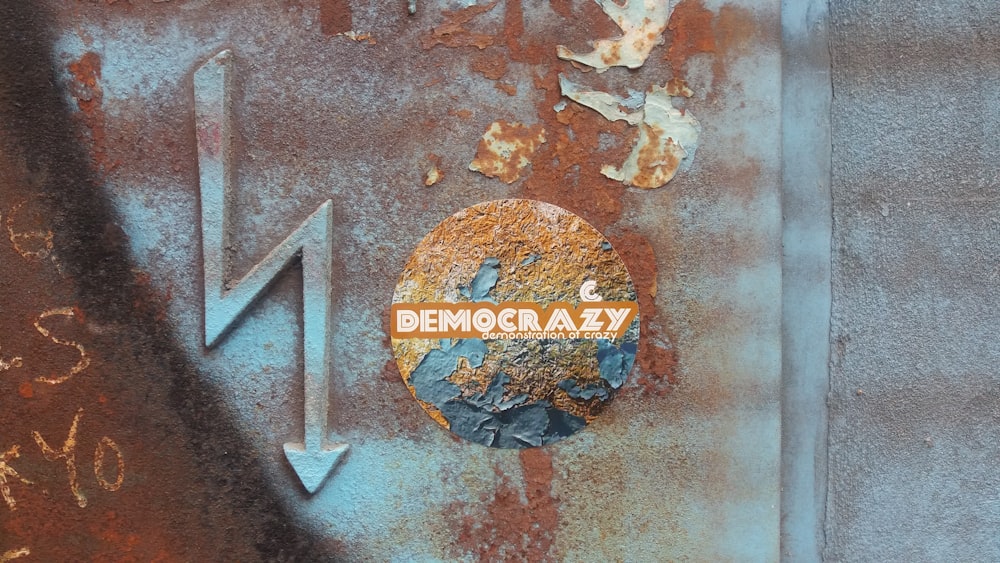 a rusted metal sign with the word democracy on it