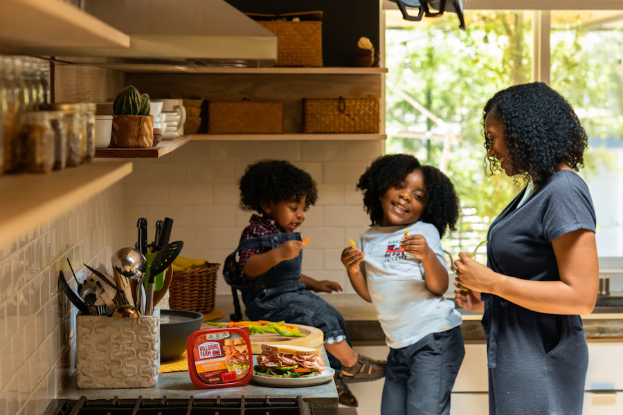 A mom cooking with her two kids in a sunny kitchen