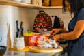 person holding knife slicing food on brown wooden chopping board