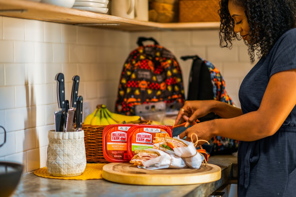 person holding knife slicing food on brown wooden chopping board