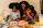 Photo of a happy young mom packing her child's bright orange lunch box with colorful snacks.
