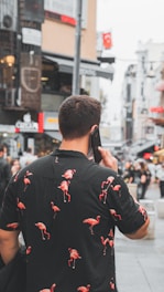 man in black and red floral jacket holding black smartphone