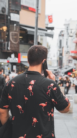 man in black and red floral jacket holding black smartphone