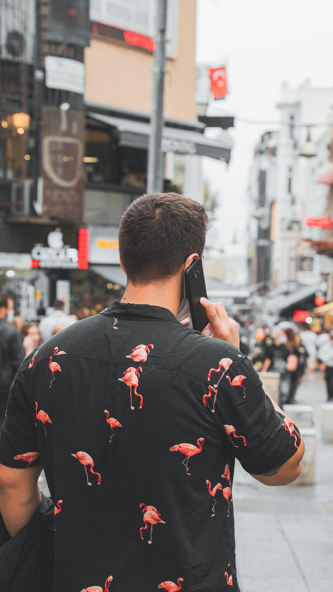 man in black and red floral jacket holding black smartphone