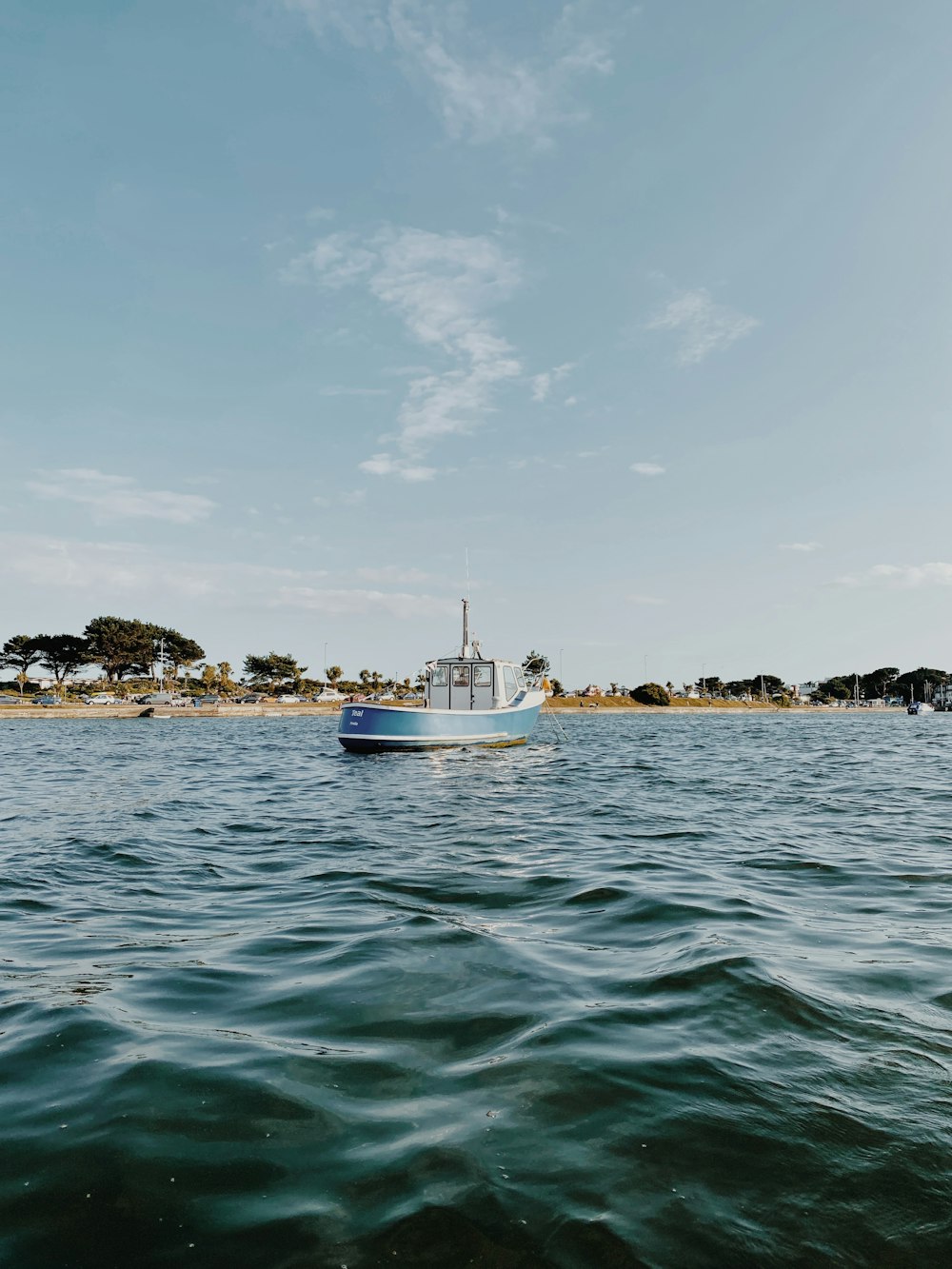 white and blue boat on sea under white clouds during daytime