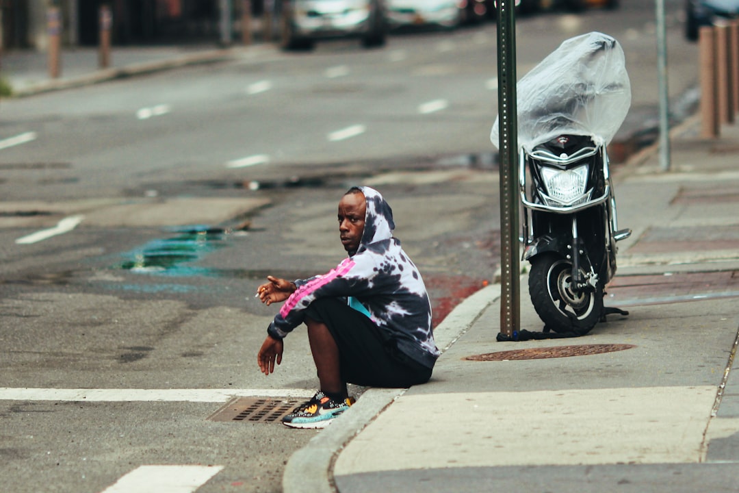 woman in blue and white hijab sitting on sidewalk during daytime