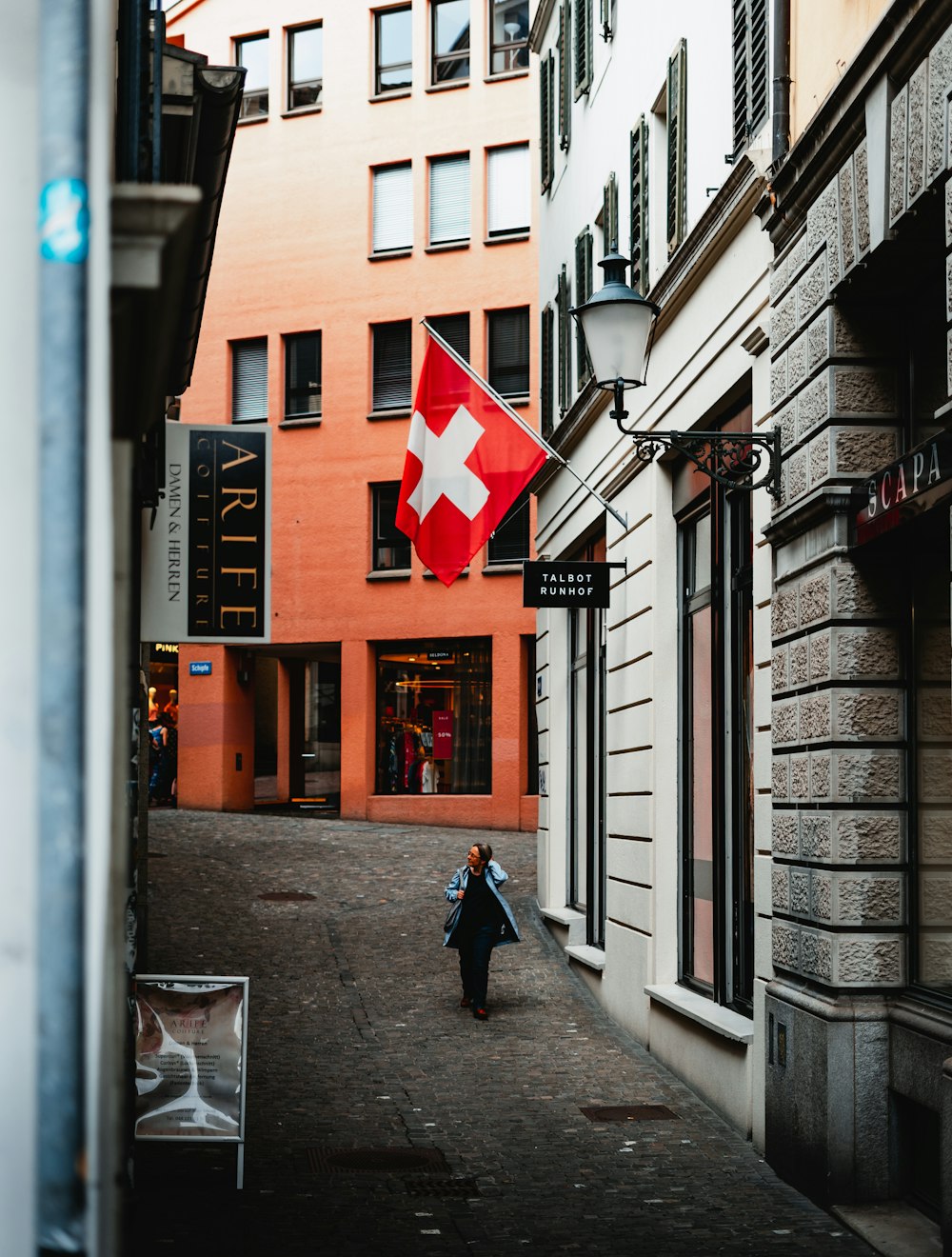 man in blue jacket walking on sidewalk during daytime