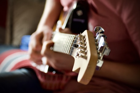 person playing brown and white electric guitar