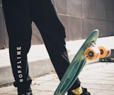 person in black pants and black nike shoes holding green skateboard