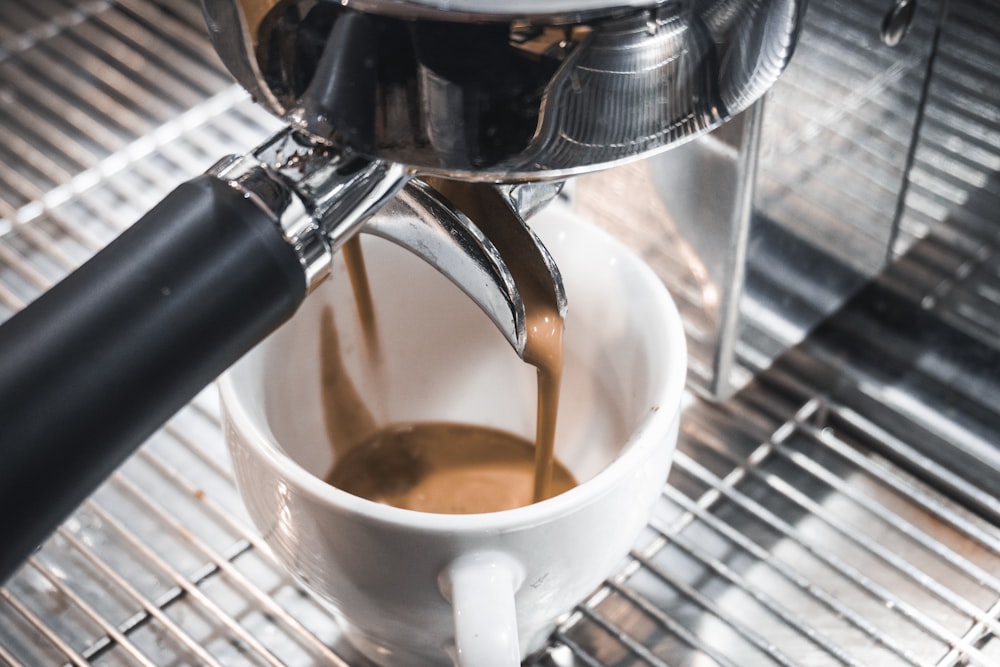 white ceramic mug on silver coffee maker