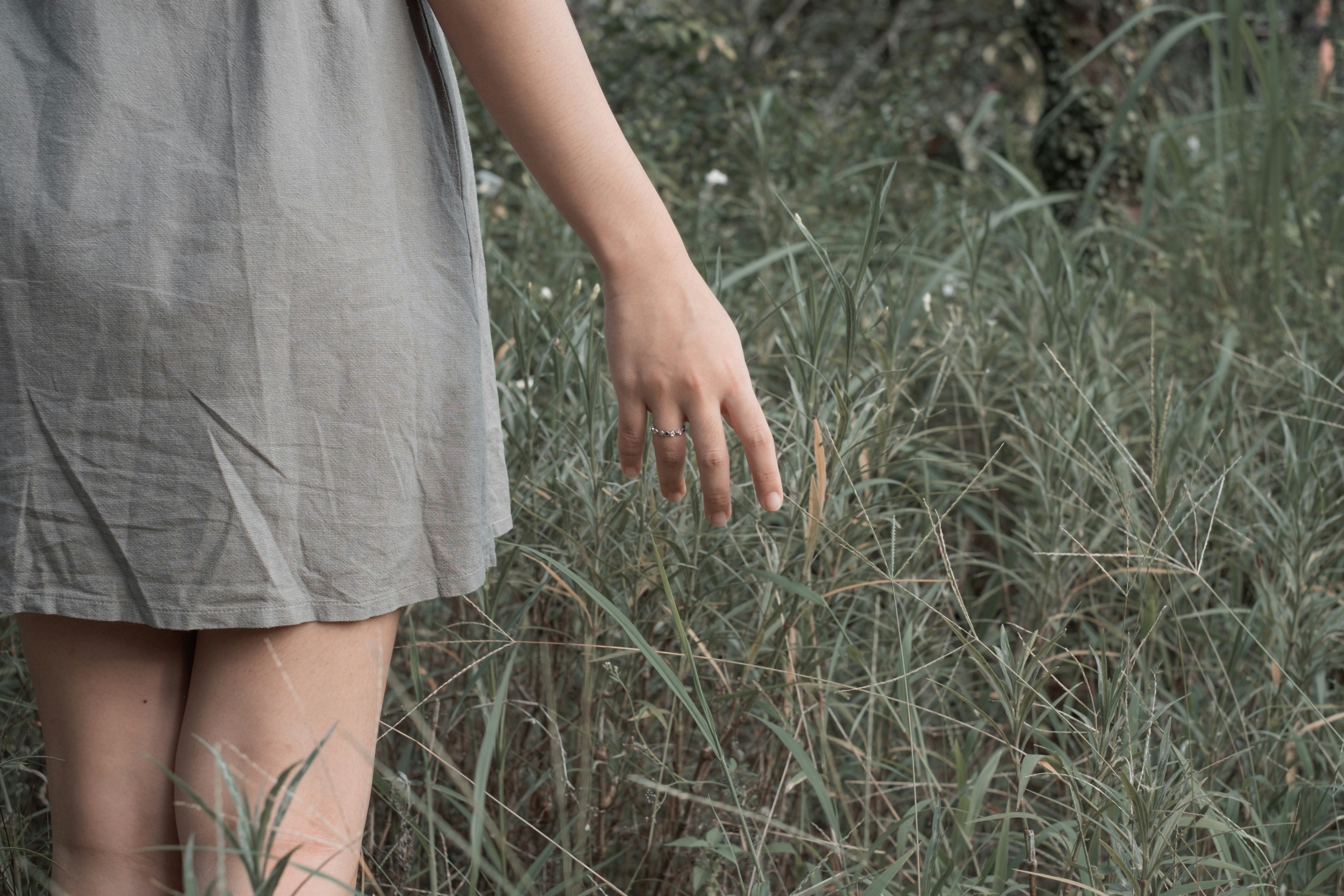 woman in gray dress standing on green grass field
