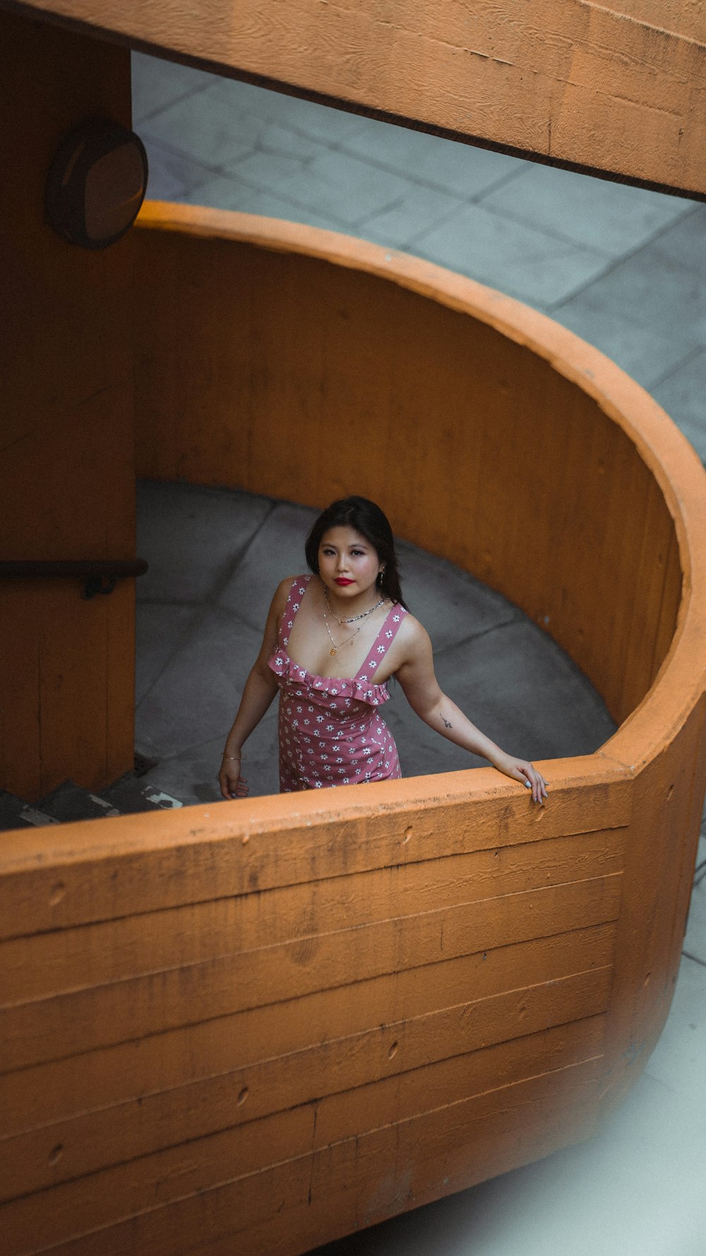 girl in pink and white floral dress in brown wooden bathtub