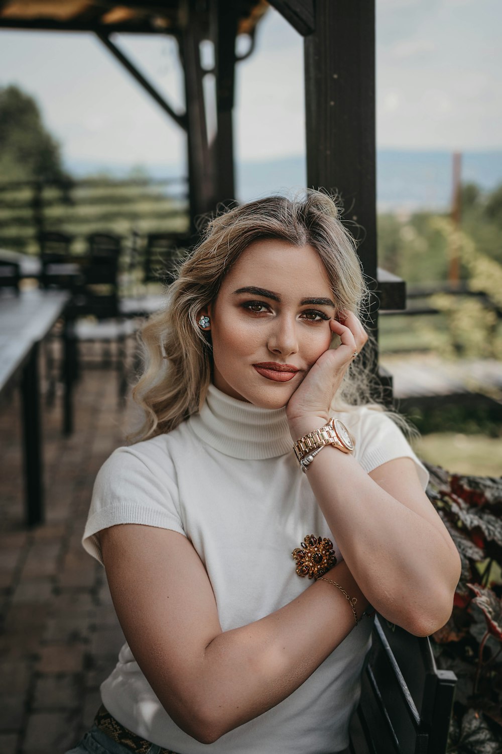 woman in white crew neck t-shirt sitting on brown wooden bench during daytime