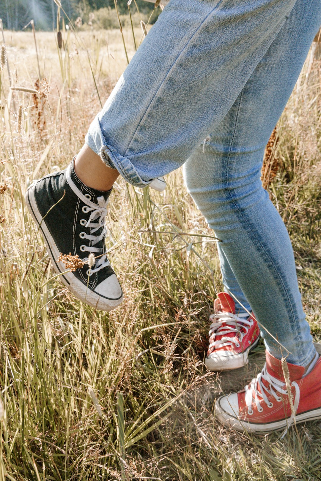 person in blue denim jeans and black and white converse all star high top sneakers