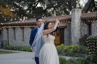 A joyful couple dancing under string lights surrounded by their guests in a charming garden.