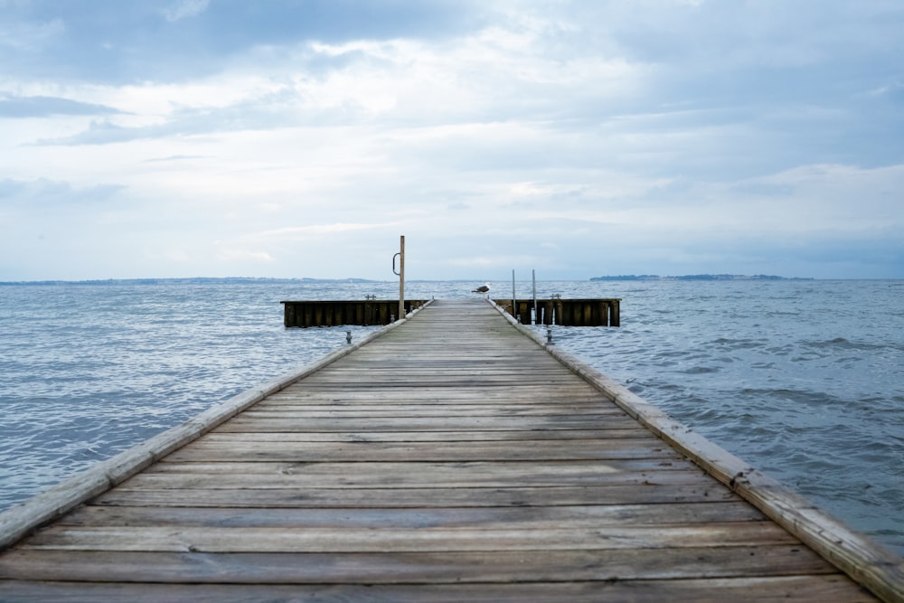 brown wooden dock on sea under white clouds during daytime