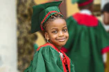 Smiling child receiving a certificate of achievement from a seasoned coach in matte forest green attire.