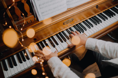 person playing brown upright piano