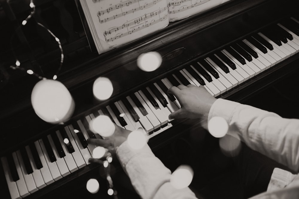 person playing piano in grayscale photography