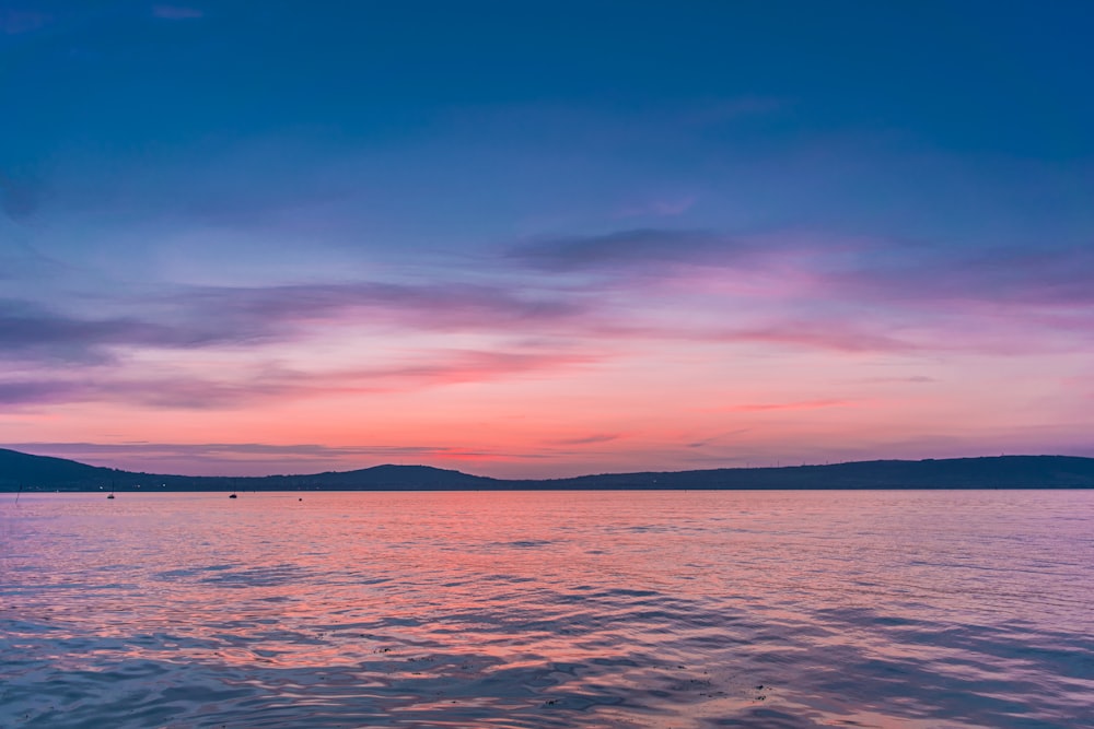 body of water under blue sky during sunset