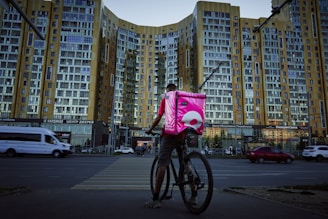 man in red shirt riding bicycle on road during daytime