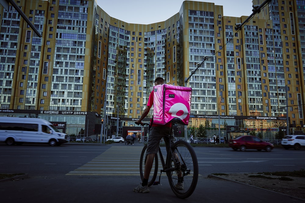 man in red shirt riding bicycle on road during daytime