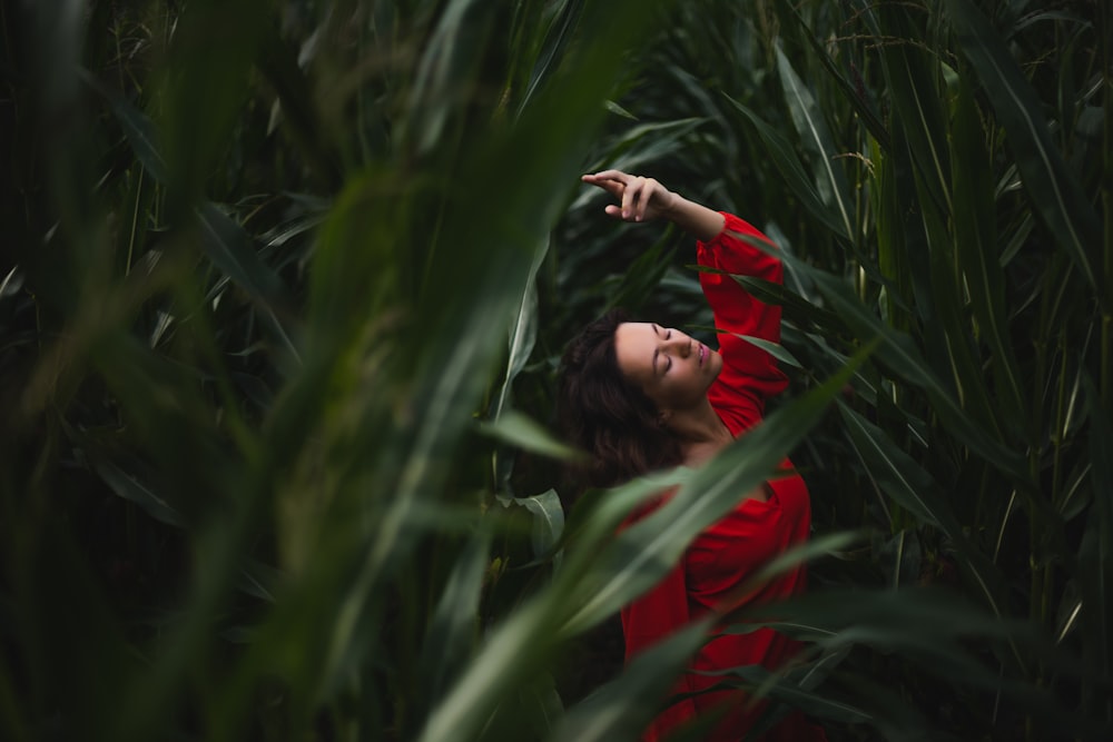 girl in red long sleeve shirt standing on green grass field during daytime