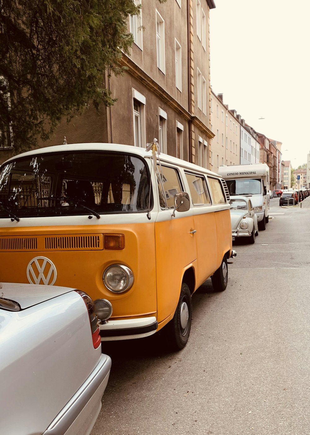 Volkswagen T-2 arancione e bianca parcheggiata sul marciapiede durante il giorno